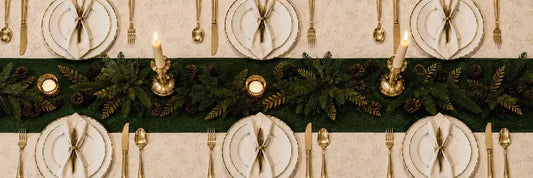 Table de Noël élégante dressée avec porcelaine fine, chandeliers en métal doré et serviettes pliées, tendances 2026