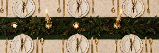 Table de Noël élégante dressée avec porcelaine fine, chandeliers en métal doré et serviettes pliées, tendances 2026