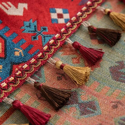 Gros plan sur les pompons artisanaux colorés d'un chemin de table bohème à motifs géométriques