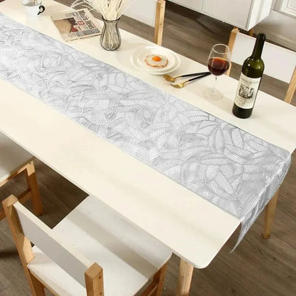 Image d'un joli chemin de table argenté au motif de feuille sur une table en bois blanc à l'apéro