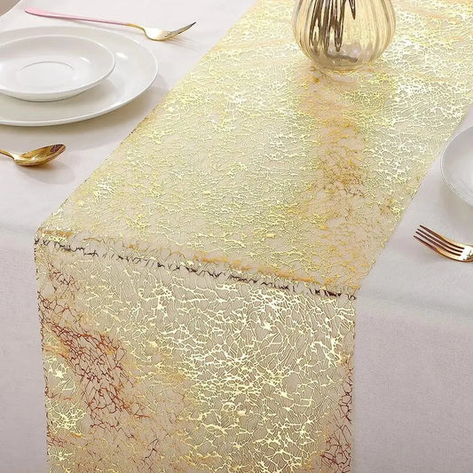 Image d'un élégant chemin de table doré au style métallique sur une nappe blanc crème avec de la jolie vaisselle blanche