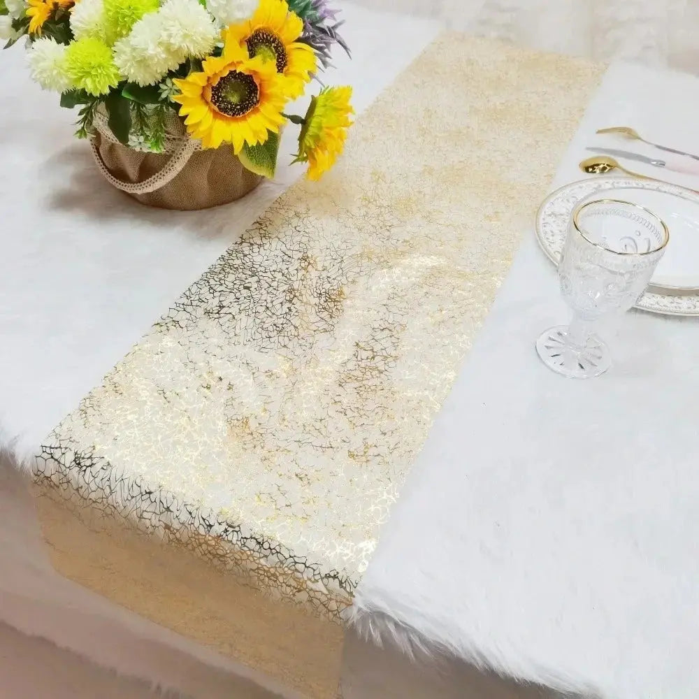 Image d'un superbe chemin de table doré au style métallique sur une nappe blanche accompagné d'un magnifique bouquet de fleurs jaunes et blanches