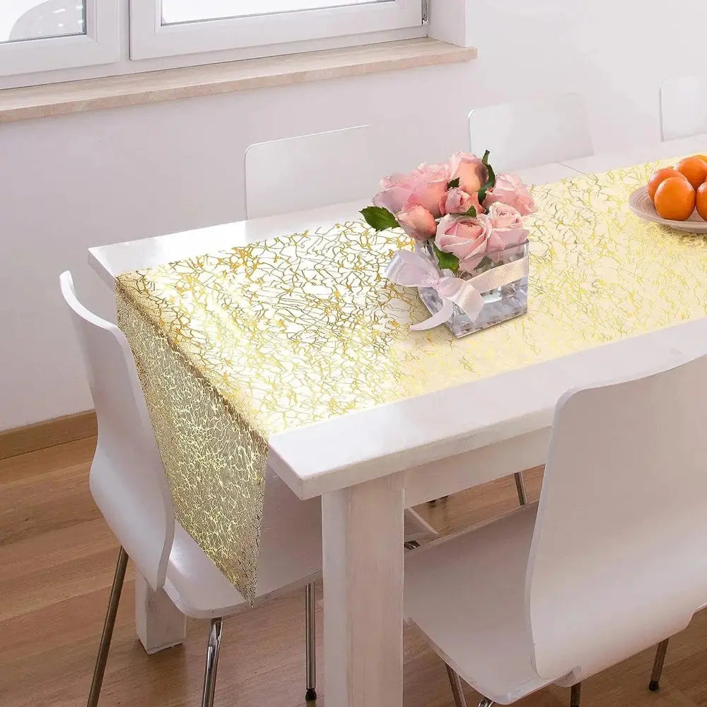 Image d'un superbe chemin de table doré au style métallique sur une jolie table en bois blanc accompagné d'un  magnifique pot de roses 