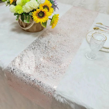 Image d'un superbe chemin de table rose doré au style métallique sur une nappe blanche accompagné d'un magnifique bouquet de fleurs jaunes et blanches