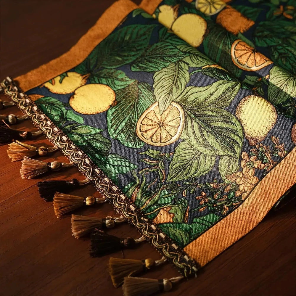 Image d'un élégant chemin de table replié sur lui-même représentant des agrumes comme motif avec de jolis petits pompons