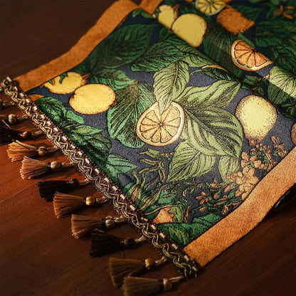 Image d'un élégant chemin de table replié sur lui-même représentant des agrumes comme motif avec de jolis petits pompons