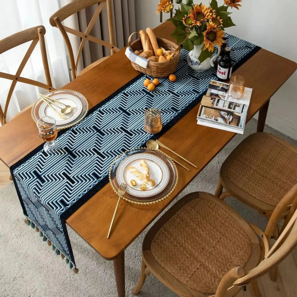 Image d'un chemin de table jacquard aux formes géométriques bleu et noir sur une table en bois vue de haut