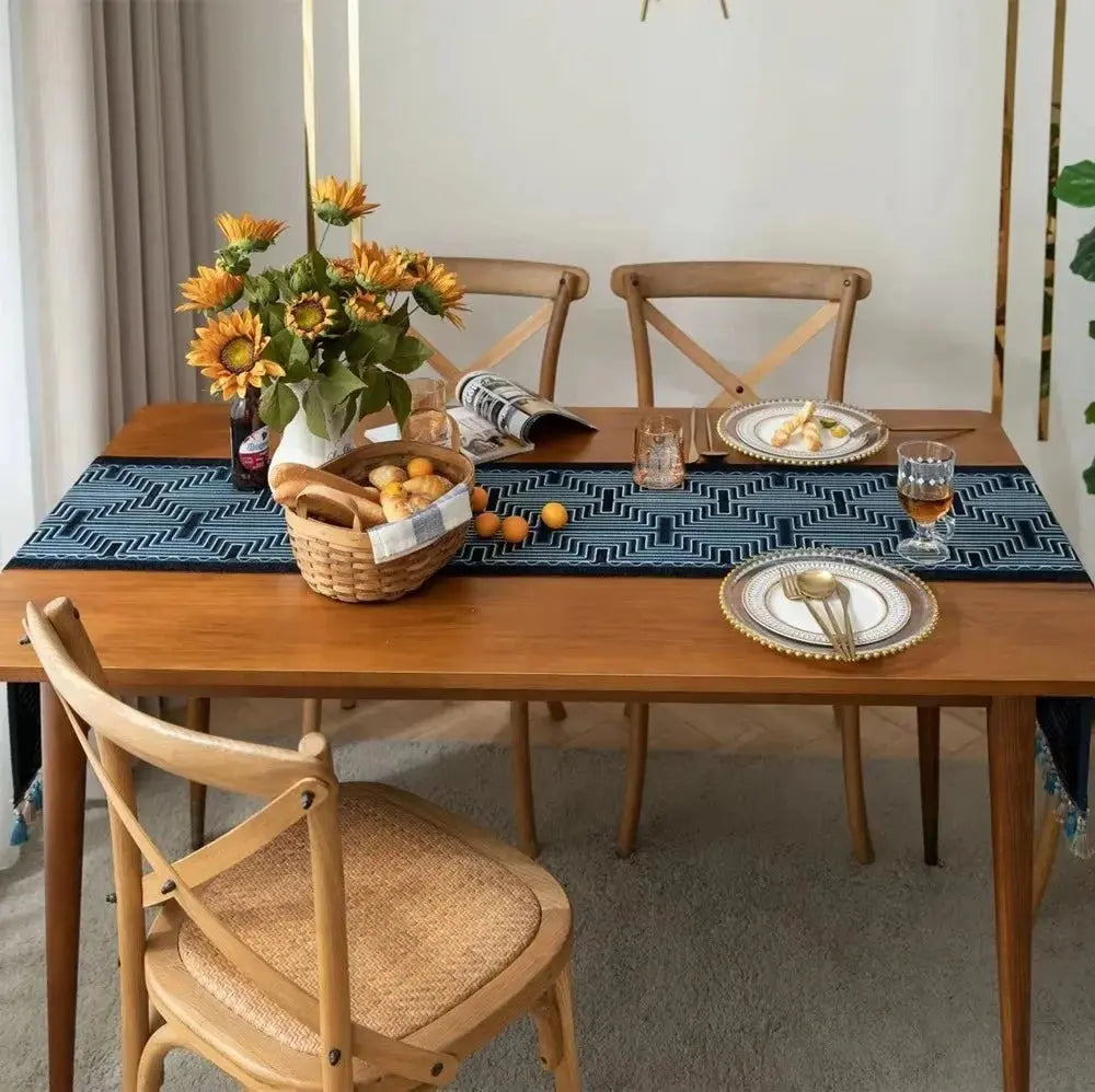 Image d'un chemin de table jacquard aux formes géométriques bleu et noir sur une table en bois sur la longueur