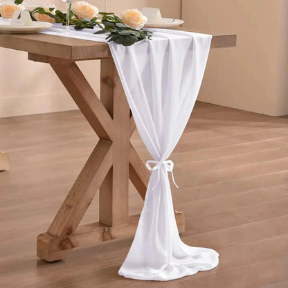 Image d'un chemin de table en mousseline blanc sur une jolie table en bois ornée de magnifiques roses crème