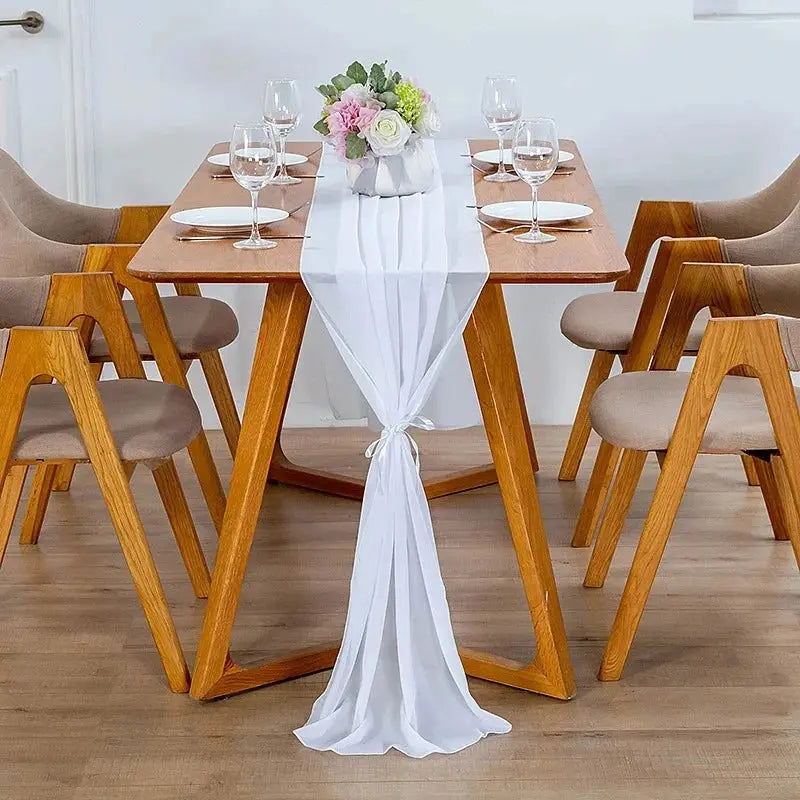 Image d'un chemin de table en mousseline blanc sur une jolie table en bois ornée d'un beau bouquet de fleurs