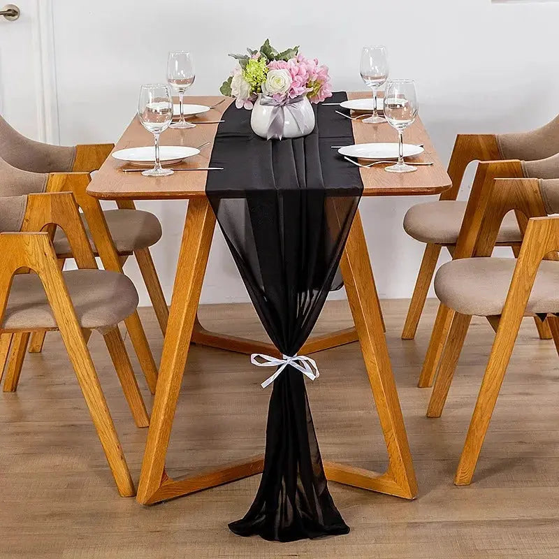 Image d'un chemin de table en mousseline noir sur une jolie table en bois ornée d'un beau bouquet de fleurs