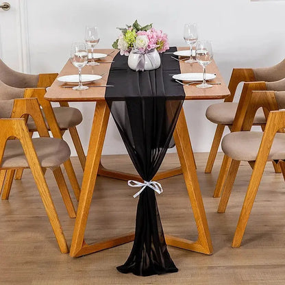 Image d'un chemin de table en mousseline noir sur une jolie table en bois ornée d'un beau bouquet de fleurs