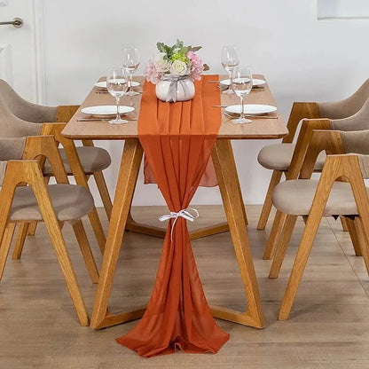Image d'un chemin de table en mousseline orange sur une jolie table en bois ornée d'un beau bouquet de fleurs