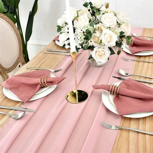 Image d'un chemin de table en mousseline rose sur une jolie table en bois ornée d'un beau bouquet de roses couleur crème et d'un chandelier doré