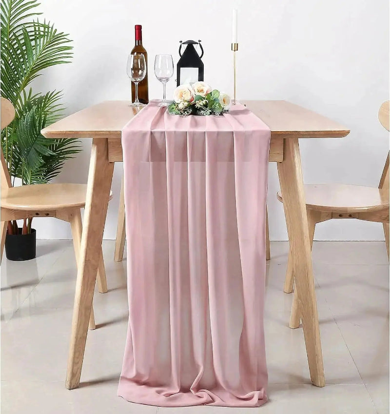 Image d'un chemin de table en mousseline rose sur une jolie table en bois dans une atmosphère romantique
