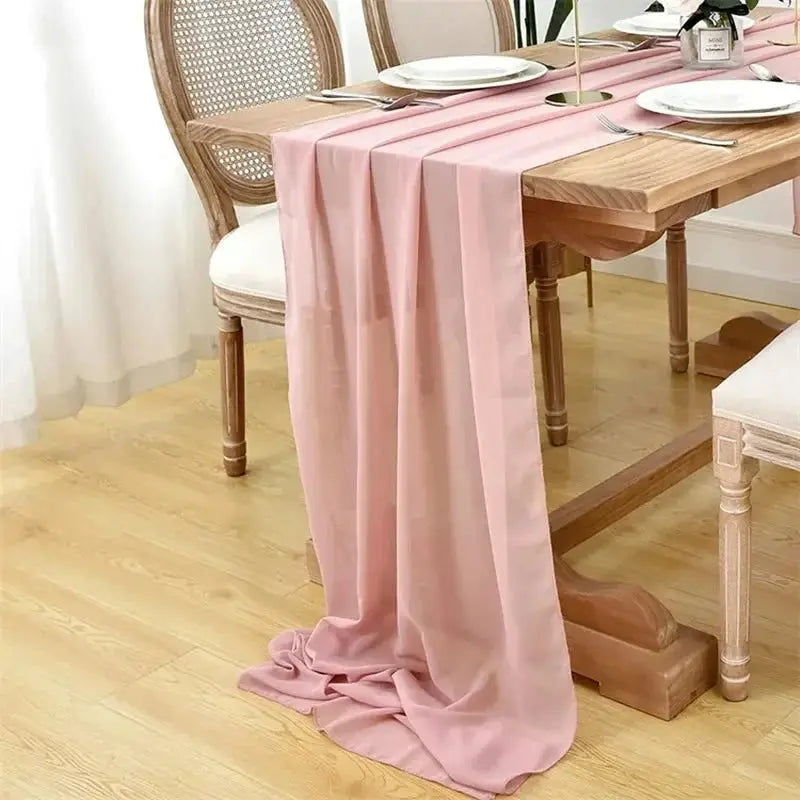 Image d'un chemin de table en mousseline rose qui a l'effet d'un voile sur une jolie table en bois