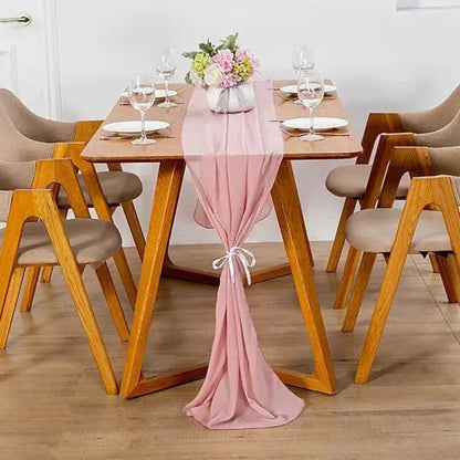 Image d'un chemin de table en mousseline rose sur une jolie table en bois ornée d'un beau bouquet de fleurs