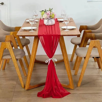 Image d'un chemin de table en mousseline rouge sur une jolie table en bois ornée d'un beau bouquet de fleurs