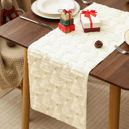 Élégant et doux chemin de table de Noël de couleur blanche crème avec de petits sapins tissés en relief, placé sur une table en bois orné de petites boîtes de cadeaux