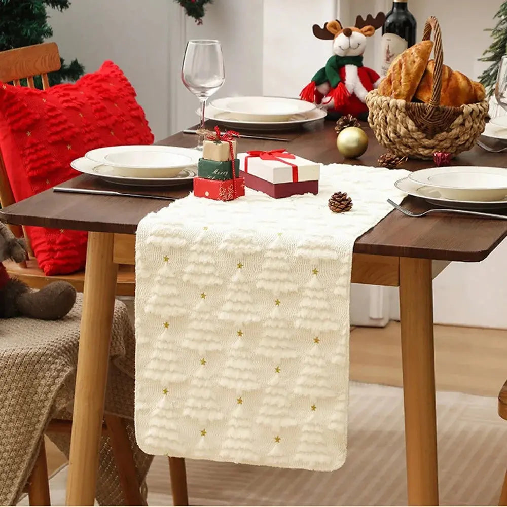 Élégant et doux chemin de table de Noël de couleur blanche crème avec de petits sapins tissés en relief, placé sur une jolie table à dîner en bois au décor des Fêtes