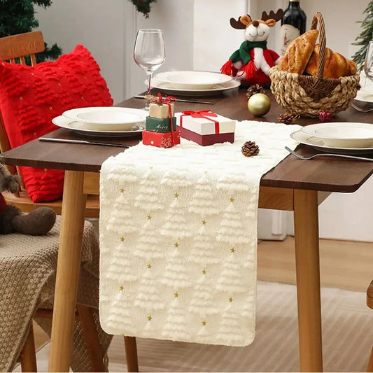 Élégant et doux chemin de table de Noël de couleur blanche crème avec de petits sapins tissés en relief, placé sur une jolie table à dîner en bois au décor des Fêtes