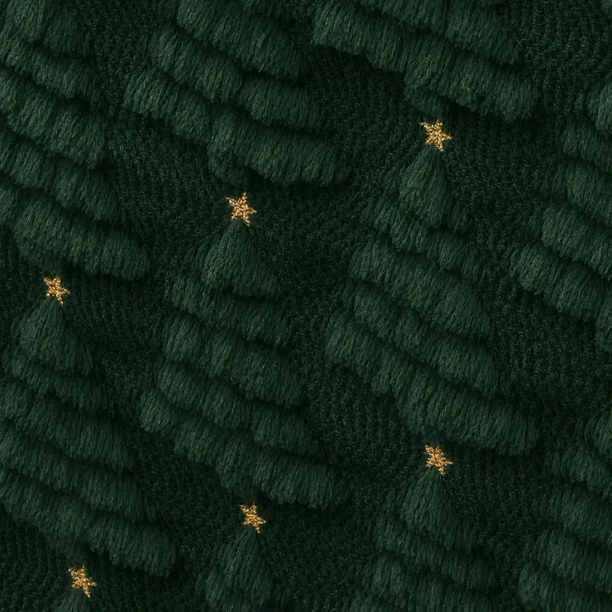 Gros plan sur le tissage en relief du chemin de table de Noël vert forêt, motifs de sapins texturés avec étoiles dorées