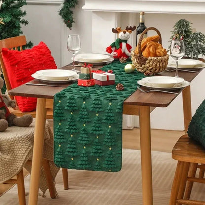 Élégant et doux chemin de table de Noël de couleur verte forêt avec de petits sapins tissés en relief, placé sur une jolie table à dîner en bois au décor des Fêtes