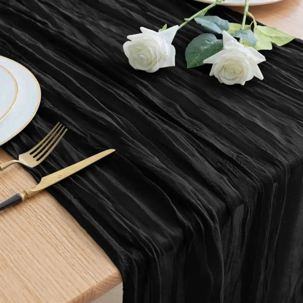 Image d'un chemin de table noir sur une table en bois garnie de deux roses blanches