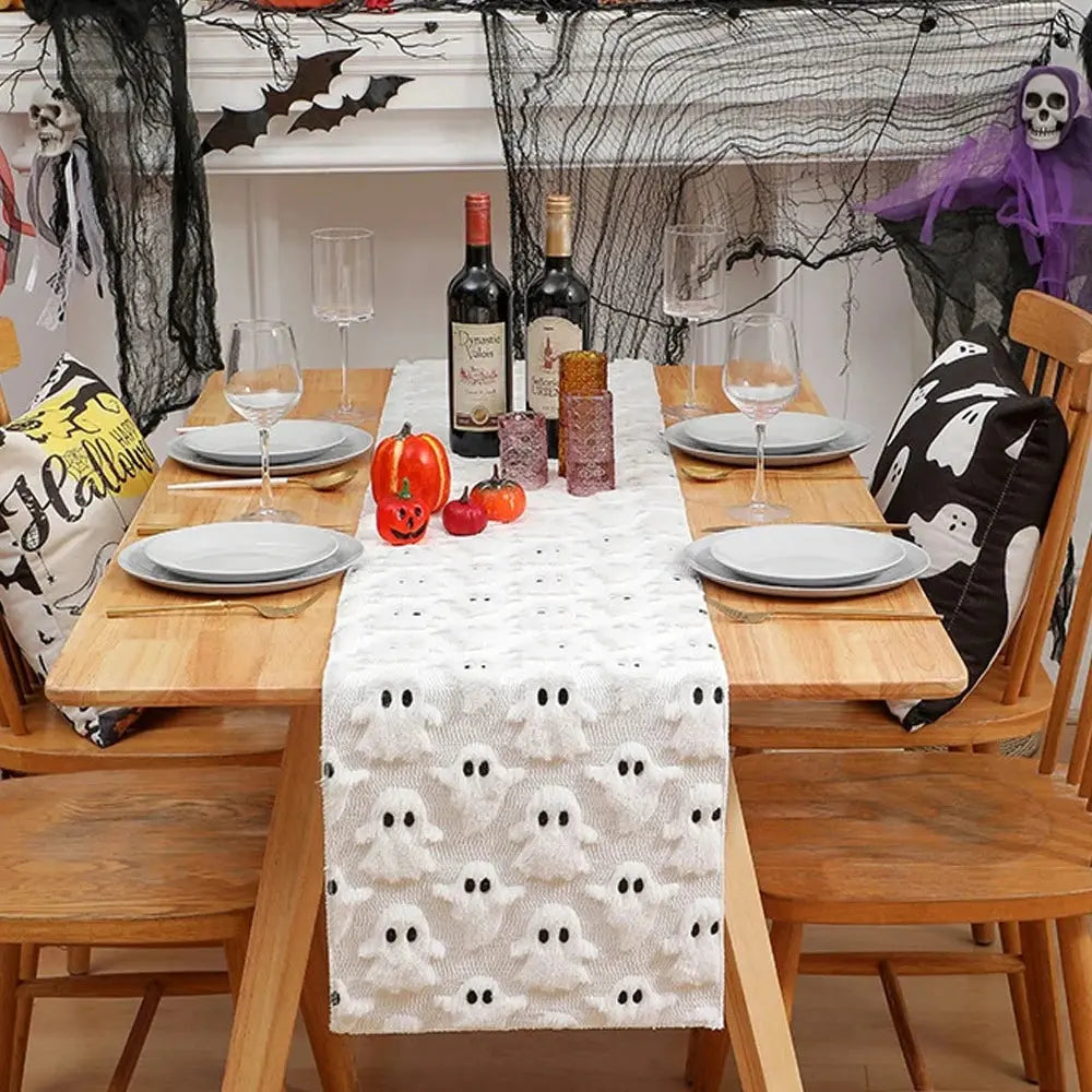 Image d'un chemin de table blanc brodé de petits fantômes sur une jolie table en bois décorée pour l'Halloween