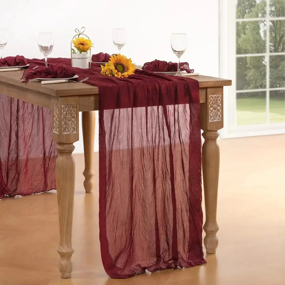 Image d'un chemin de table rouge vin sur une jolie table à dîner en bois garnie de tournesols