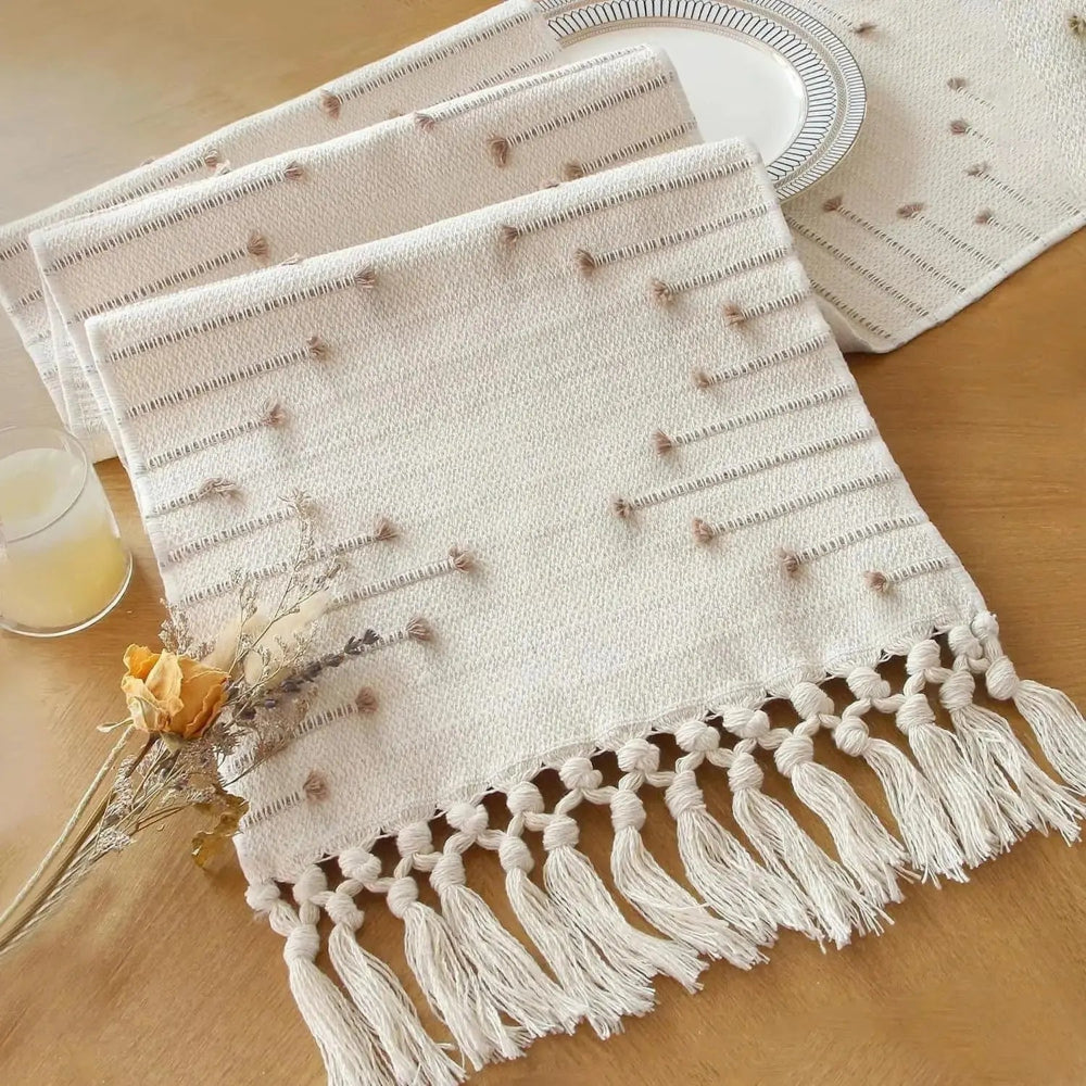 Image d'un chemin de table de couleur crème en coton replié sur lui-même avec ses jolies franges