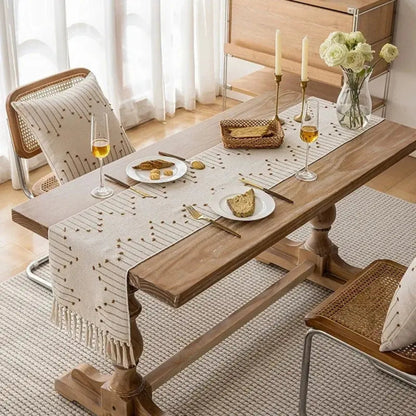 Image d'un chemin de table avec ses motifs originaux de couleur marron sur une table en bois accompagnée d'un vase de roses blanches, de verres à vin et de bougies