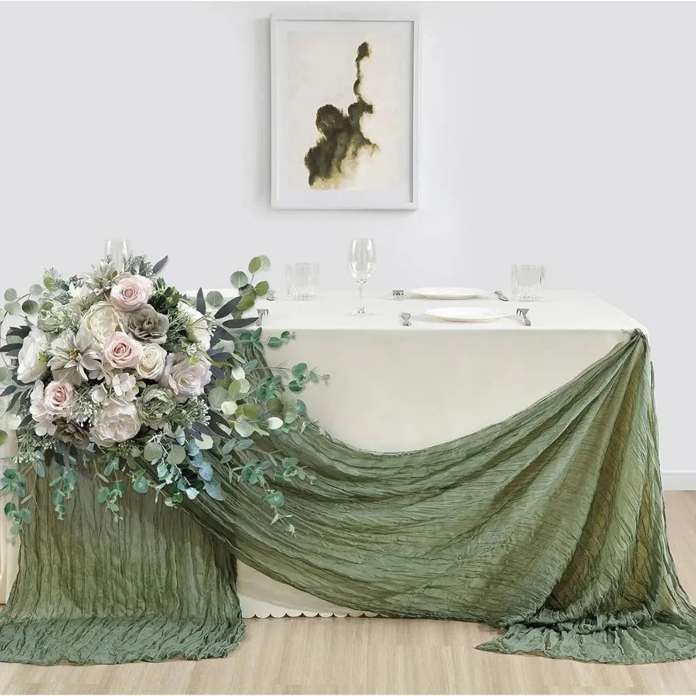 Image d'une belle table ornée d'un chemin de table vert sauge et d'un immense bouquet de fleurs pour une occasion spéciale