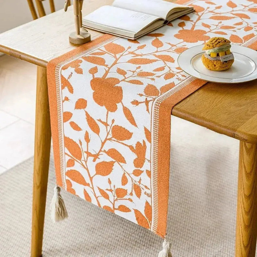 Image d'un magnifique chemin de table de style vintage ayant comme motifs des feuilles d'automne sur une table en bois mince