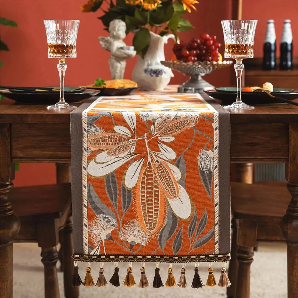 Image d'un magnifique et coloré chemin de table de style vintage ayant comme motifs des épis sur une table en bois joliment dressée de couverts et de verres à vin