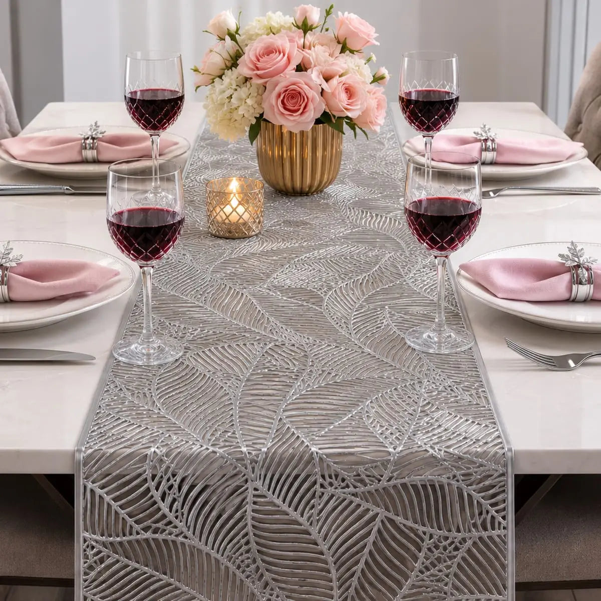 Chemin de table vinyle argenté au motif de feuille sur table dressée élégante, avec roses roses, verres à vin et bougie