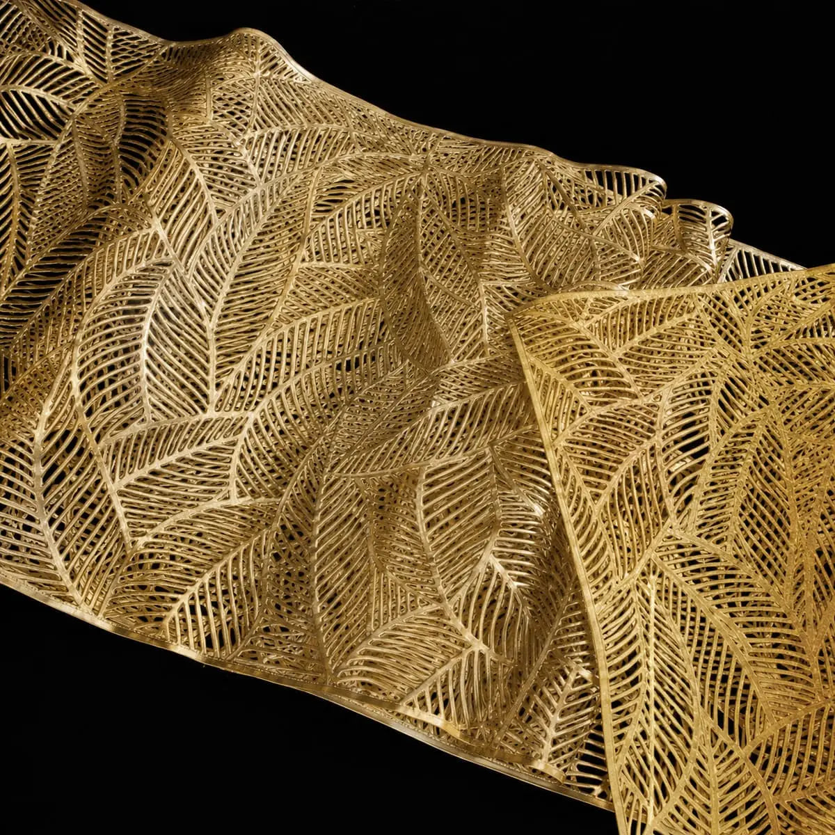 Gros plan sur le motif de feuille ajouré du chemin de table vinyle doré, texture détaillée au fini brillant