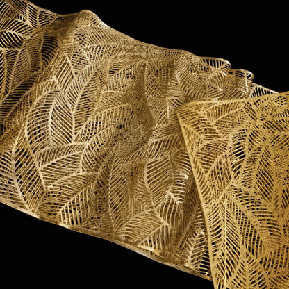 Gros plan sur le motif de feuille ajouré du chemin de table vinyle doré, texture détaillée au fini brillant