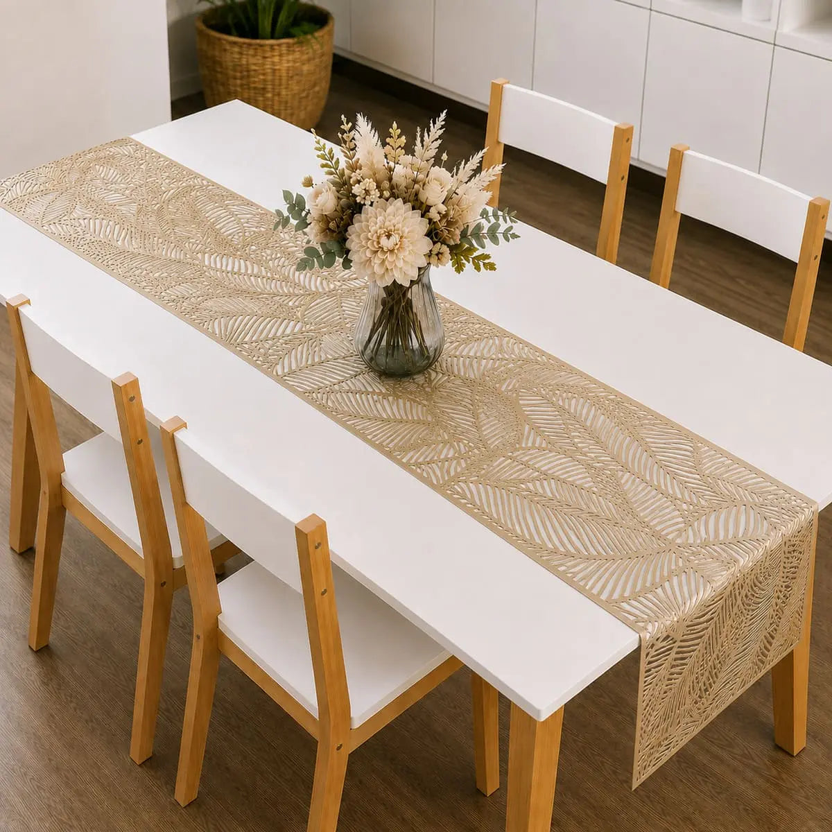 Chemin de table vinyle doré au motif de feuille sur table à manger blanche, avec bouquet de fleurs séchées