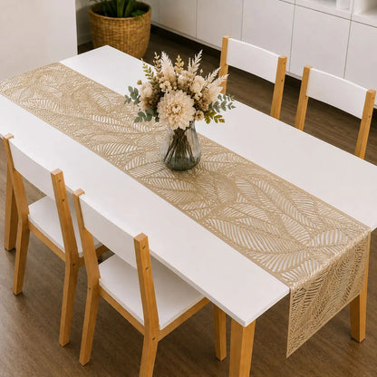 Chemin de table vinyle doré au motif de feuille sur table à manger blanche, avec bouquet de fleurs séchées