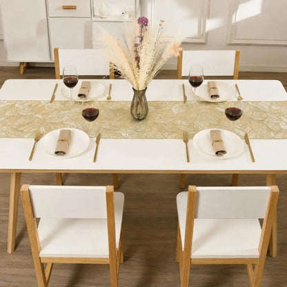 Chemin de table vinyle doré au motif de feuille sur une table à dîner dressée pour quatre, avec verres à vin et fleurs séchées