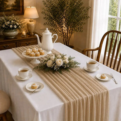 Chemin de table voilage plissé beige sur table dressée pour le thé, avec théière blanche, tasses et pâtisseries