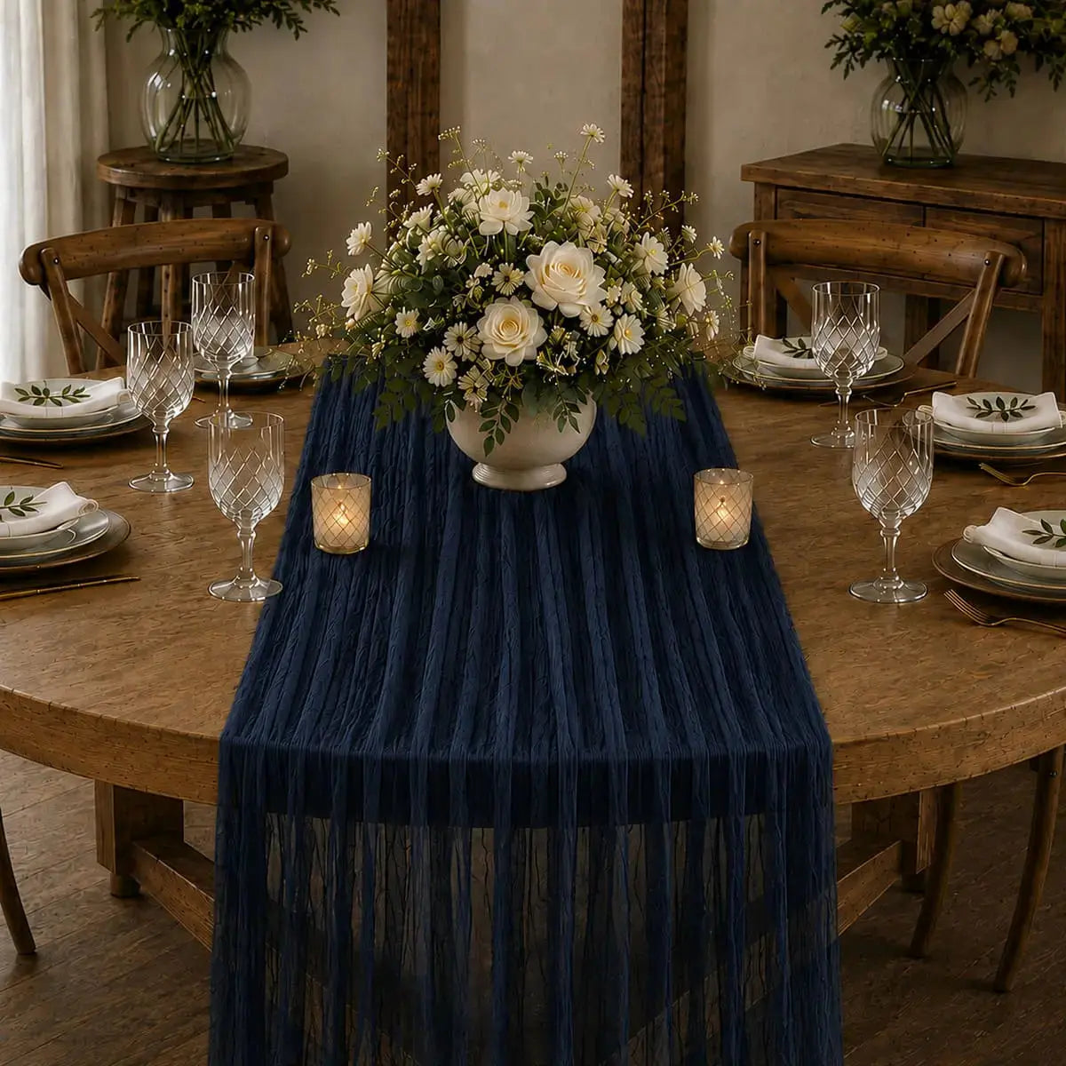 Chemin de table voilage plissé bleu marine sur table dressée avec bouquet blanc et bougies