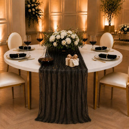 Chemin de table voilage plissé noir sur table ronde, ambiance romantique avec roses blanches, bougies et cadeau