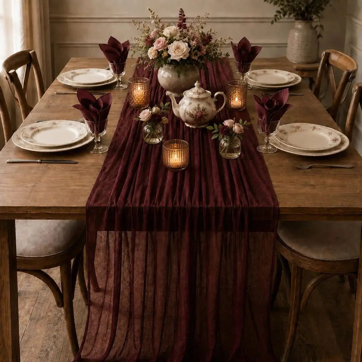 Chemin de table voilage plissé rouge vin sur table dressée d'automne avec bouquet de roses, théière fleurie et bougies