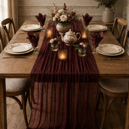 Chemin de table voilage plissé rouge vin sur table dressée d'automne avec bouquet de roses, théière fleurie et bougies