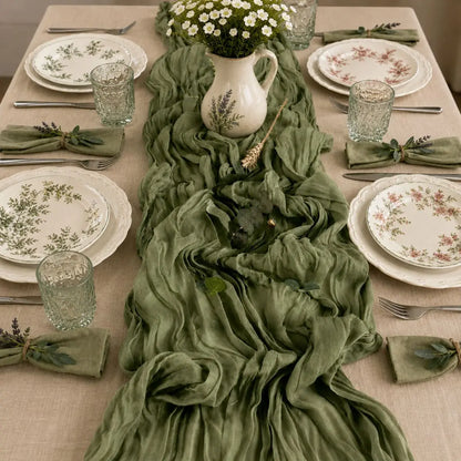 Chemin de table voilage plissé vert sauge sur table dressée champêtre avec fleurs blanches et vaisselle fleurie