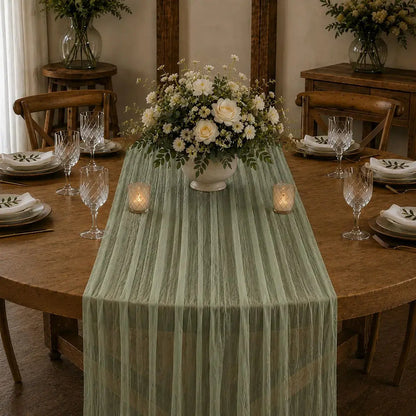 Chemin de table voilage plissé vert sauge sur table élégante avec fleurs blanches