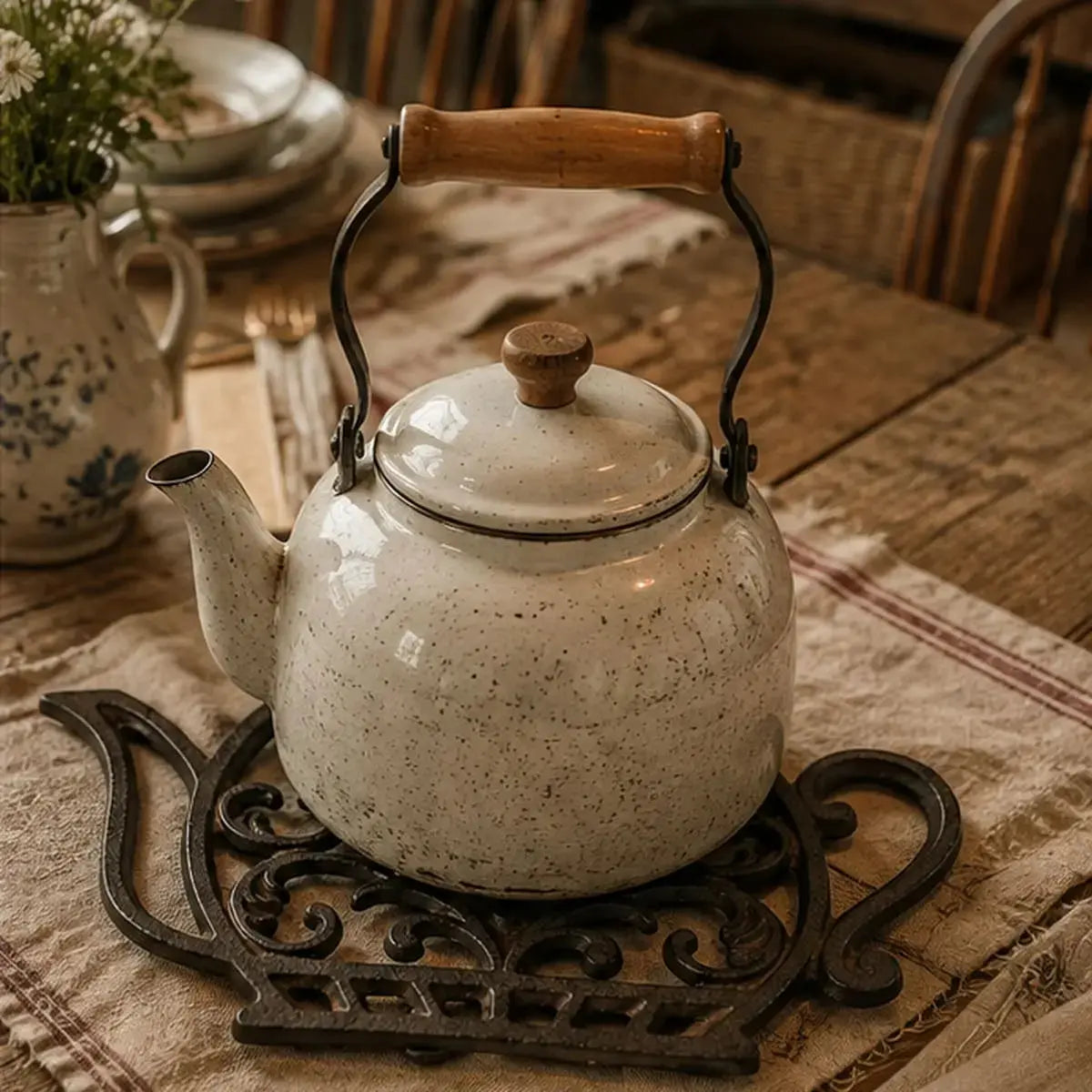 Dessous de plat en fonte en forme de théière soutenant une véritable théière vintage sur une table rustique
