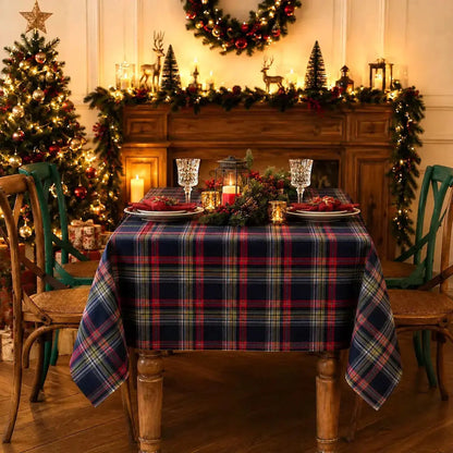 Nappe de Noël à carreaux bleu sur une table de quatre personnes mais dressée pour deux, devant un manteau de cheminée décoré de rennes